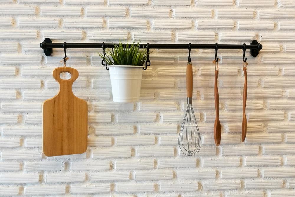 Wooden cookware and plant on flower pot hanging on white brick wall, Kitchen decoration interior